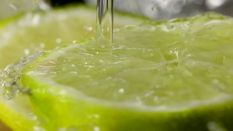 pouring water on half cut lime in slow motion, fresh fruit concept, extreme macro shot