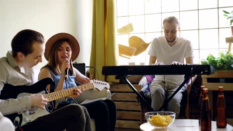 smiling musicians members of popular band are rehearsing at home singing and playing the keyboard and the guitar. musical instruments and creative people concept.