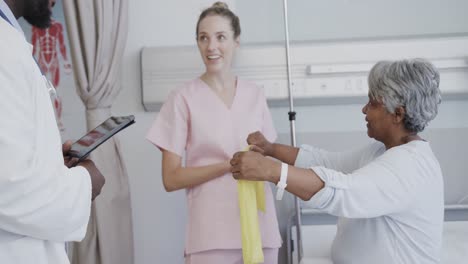 médico masculino diverso con tableta y fisioterapeuta femenina con paciente femenina mayor, cámara lenta