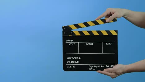 film slate or movie clapperboard with blue green screen background. film crew man hold and hit film slate in the frame. clapping film slate. video production chroma key background. video production.