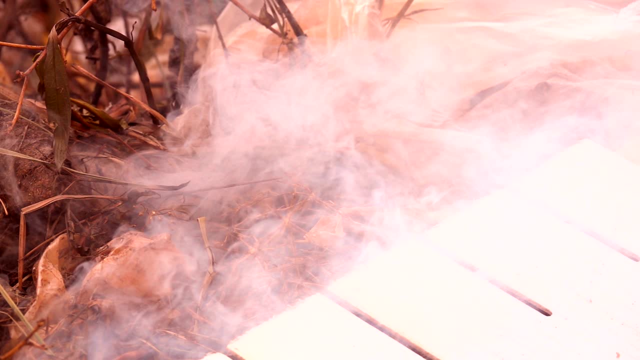 fuego en cámara lenta quemando bolsa de basura en el amanecer fondo oscuro.