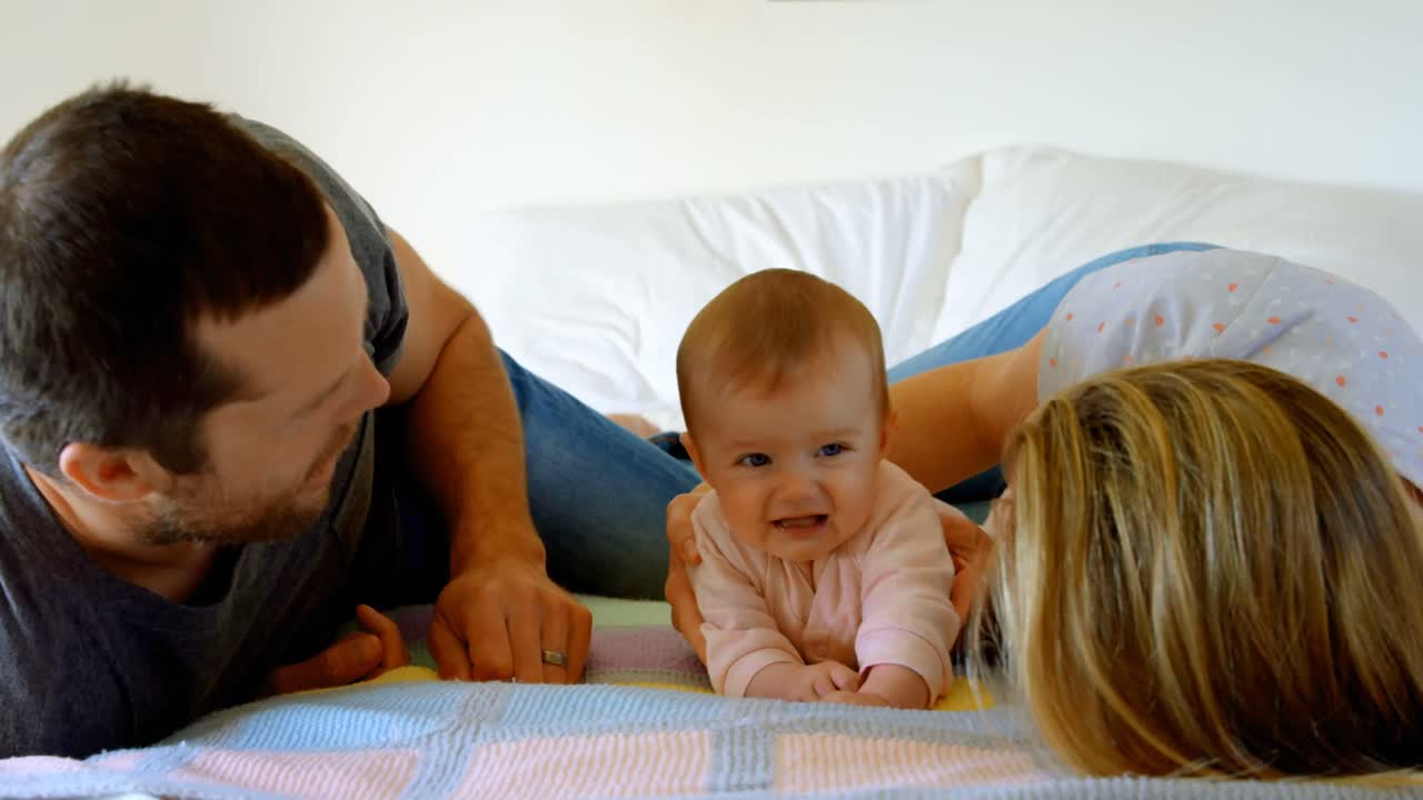 백인 부모가 집에서 침대에 아기와 함께 누워 있습니다. 4k