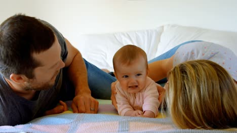 caucasian parents lying with their baby on bed at home 4k