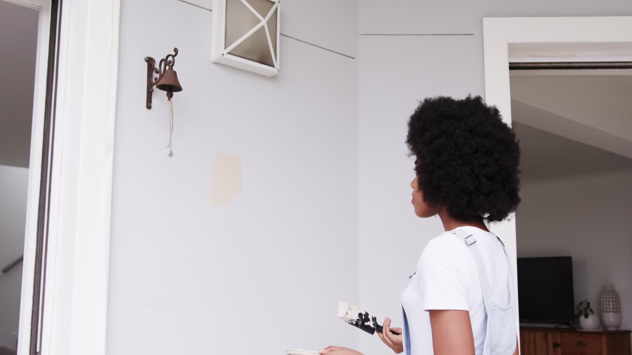 African American woman in white tee overalls holding brush tray testing swatch color, copy space