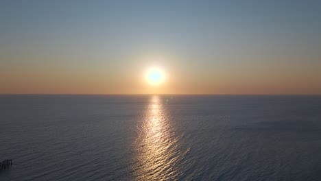 drone glides laterally from north to south while facing the setting sun. the reflection dances across the ocean’s surface, capturing motion, light, and color in a graceful sunset journey.