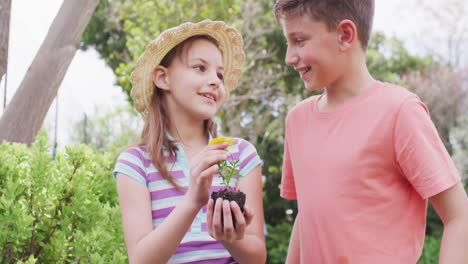 Happy-caucasian-siblings-working-in-garden-on-sunny-day