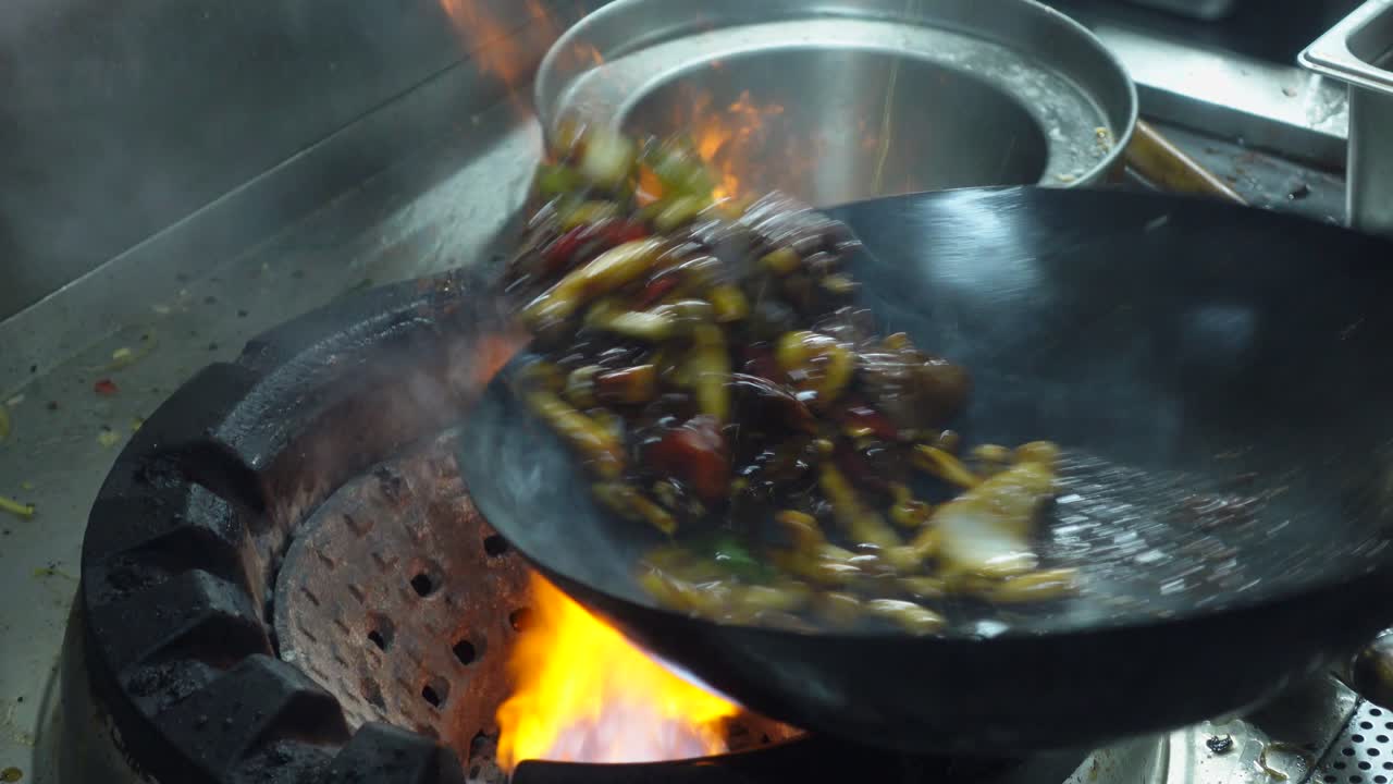 在商業廚房裡，食材在熱鍋中用燃氣火焰翻炒。特寫鏡頭。