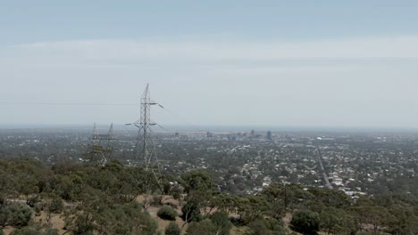 torres de alta tensión en la montaña con una visión general de la ciudad de adelaide en australia en un día soleado