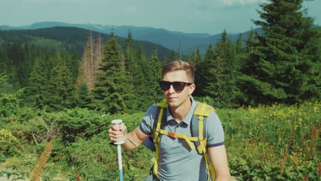 a young tourist rises up the mountain uses trekking sticks against the background of a picturesque s