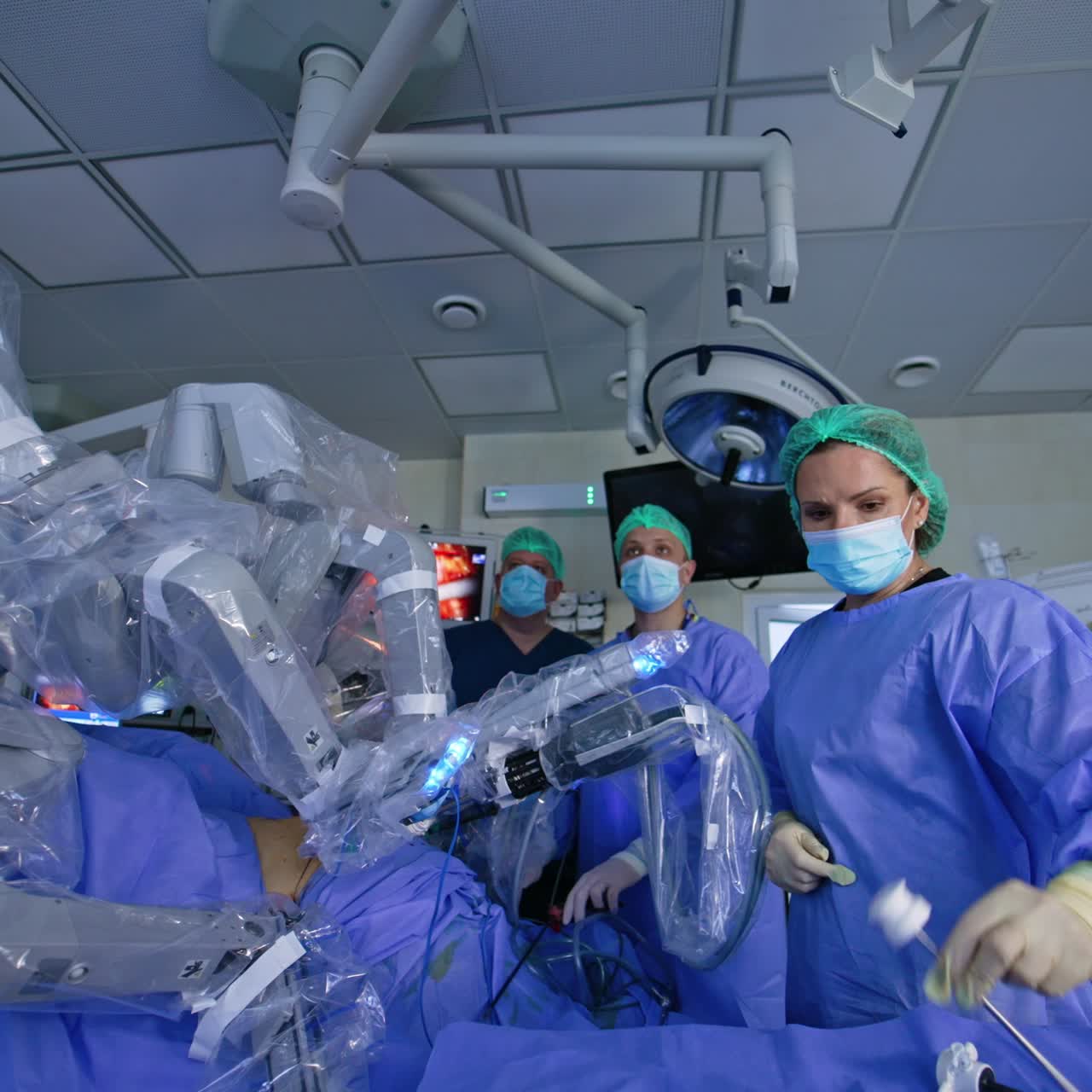 Innovative robotic equipment operating the patient. Robotic arms covered with plastic move in the patient's body. Doctors monitoring the process on the screen