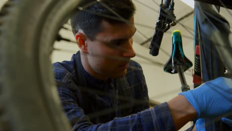 Man-repairing-bicycle-in-workshop-4k