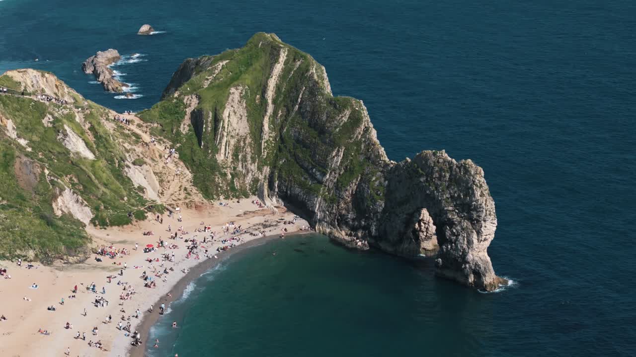 High aerial orbit right over Durdle Door beach and surrounding cliffs