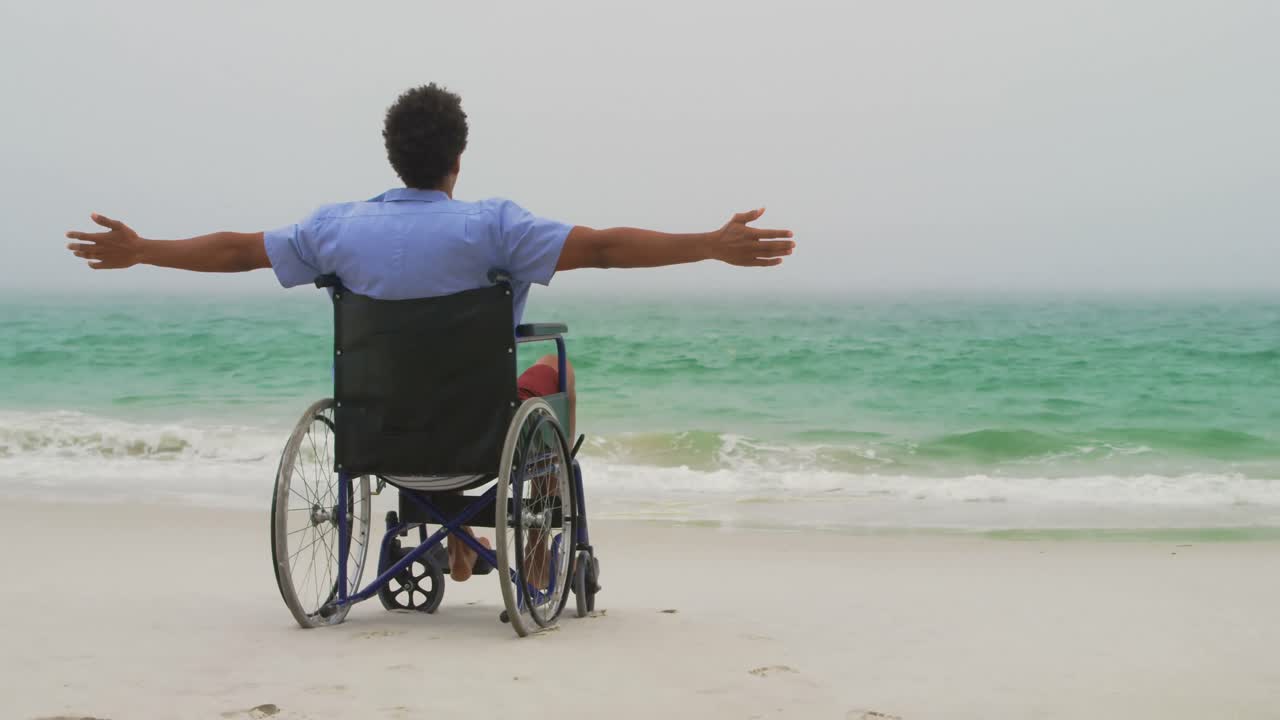 Rear view of African American man sitting with arms outstretched on wheelchair with arms outstretche