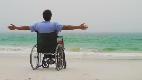 Rear-view-of-African-American-man-sitting-with-arms-outstretched-on-wheelchair-with-arms-outstretche