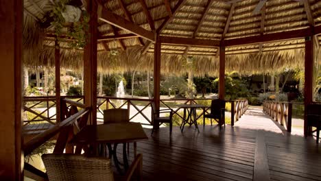 thatched wooden gazebo with tables and chairs built over pond, luxury resort