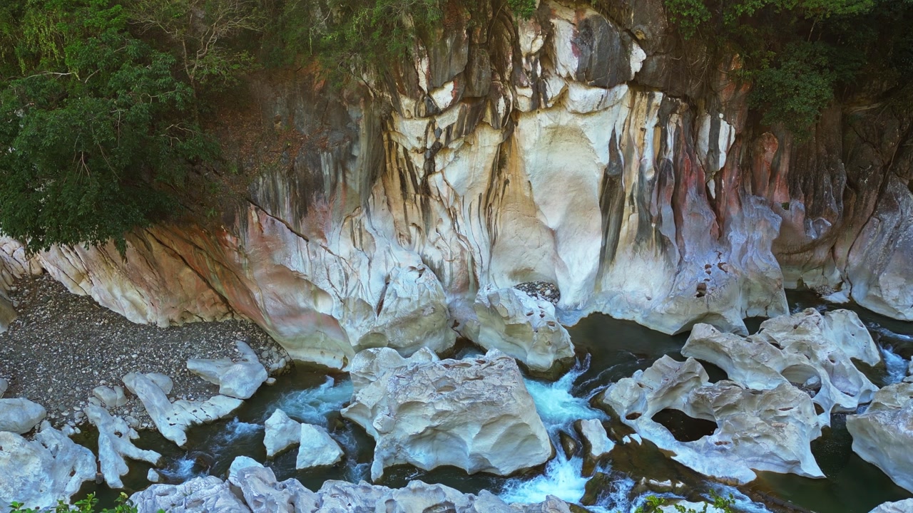 A slow aerial shot moves sideways over Tinipak River’s large white rock formations, clearly showing the river’s flowing current amidst the striking natural landscape in Tanay Rizal.