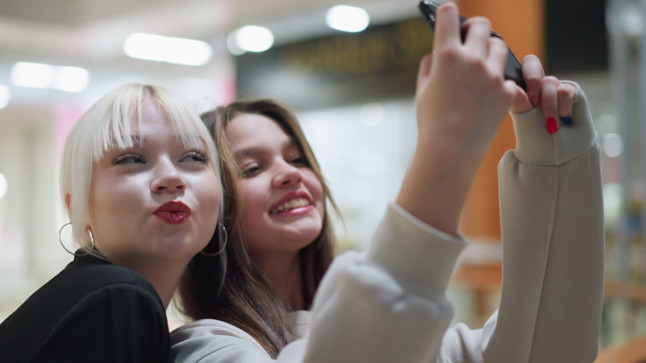 Side view of siblings recording video on smartphone while enjoying fun moment together indoors showing playful expressions youthful lifestyle bonding and entertainment