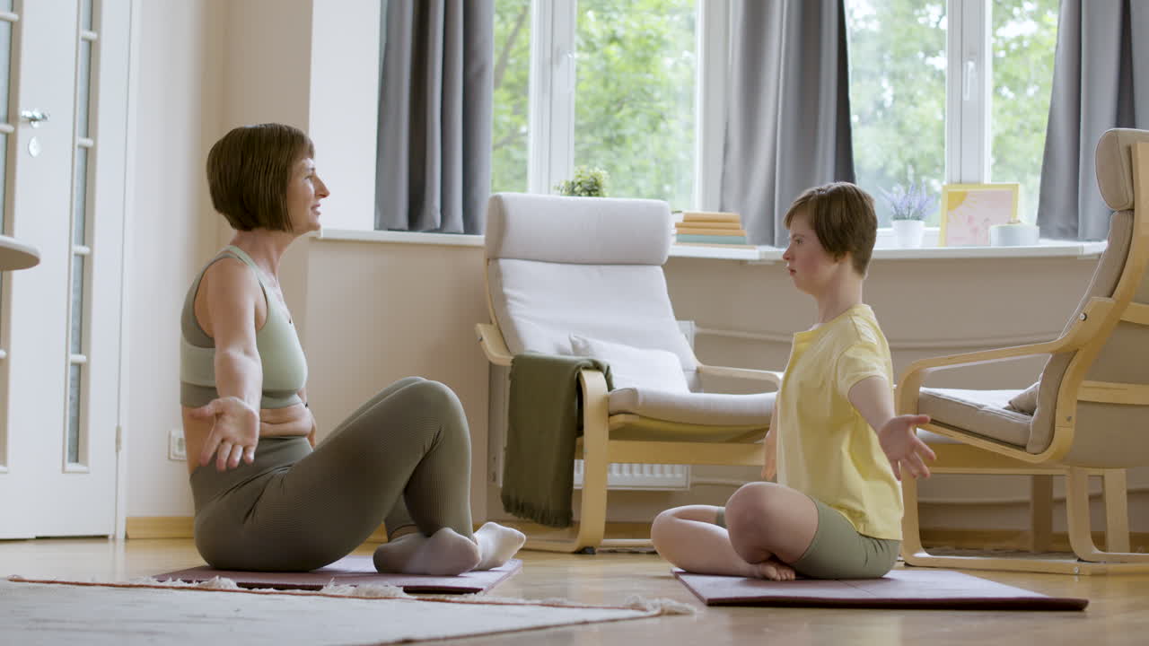 Mother and daughter sitting on yoga mat, doing yoga posture