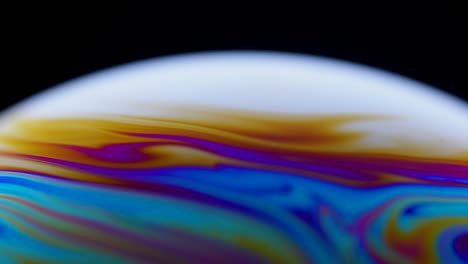 colorida superficie de cerca de una burbuja de jabón con fondo psicodélico abstracto y patrones en fondo negro. colores vívidos del arco iris en patrones extraños y extraños. de cerca. movimiento lento