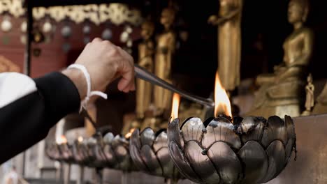 people are filling up oil into the candle holders in a buddhist temple with a belief that this will improve their fortunes and remove bad lucks