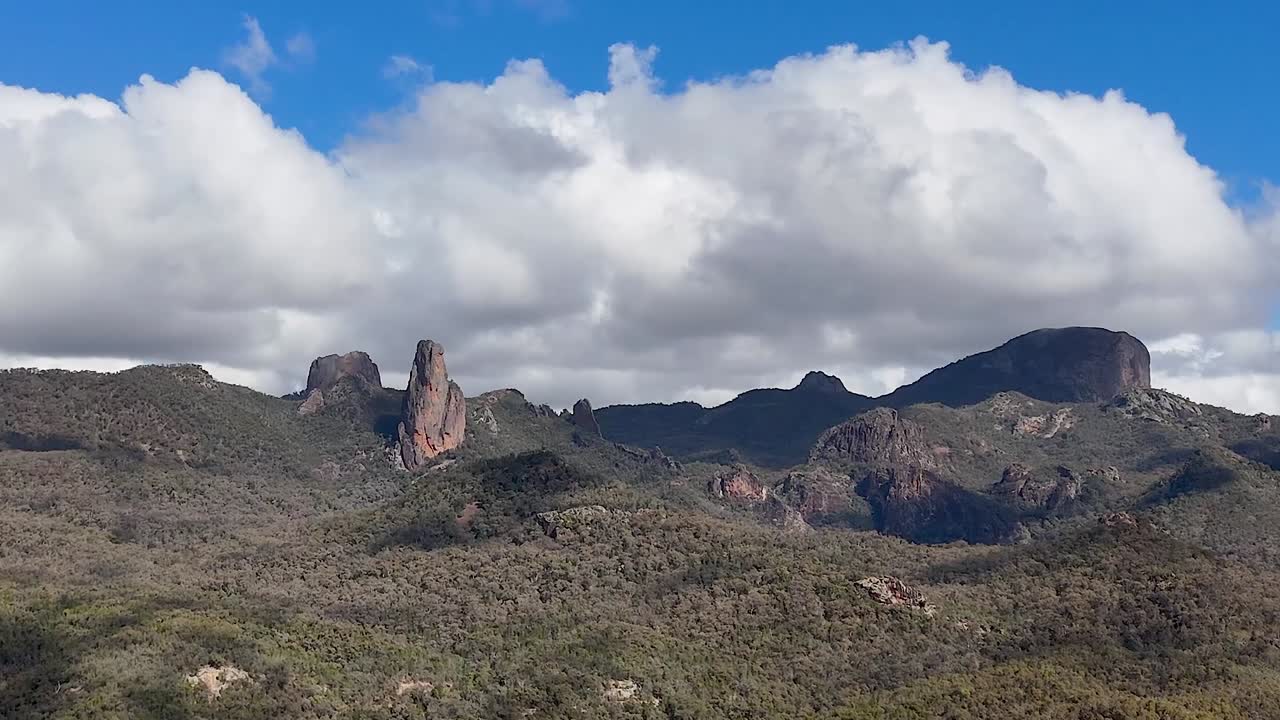 Ombre di nuvole spettacolari si estendono su antiche formazioni rocciose vulcaniche e fitte colline di boscaglia australiana.