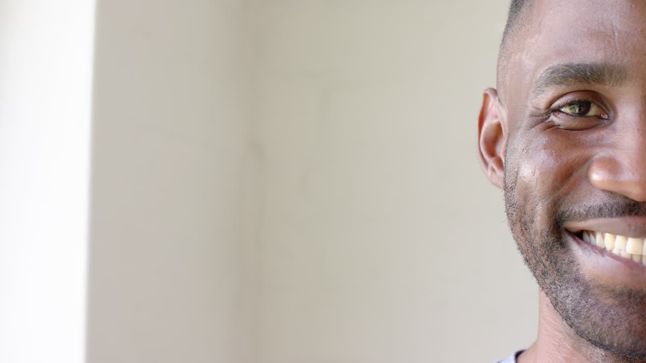 Uomo africano sorridente che risponde a un segnale fuori campo mentre è rivolto verso la luce della finestra in studio, spazio per la copia.