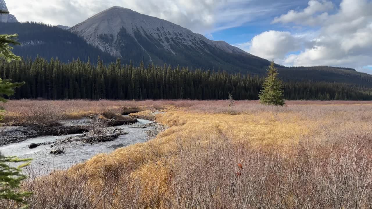 Panning shot with the river running through the mountain valley.