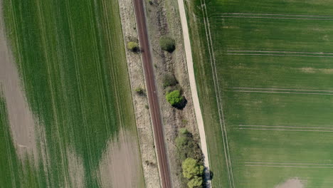 Vía-De-Tren-Rodeada-De-Tierras-De-Cultivo-Simétricas,-Sobrevuelo-De-Drones