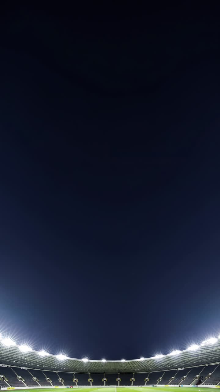 Foto grandangolare di uno stadio illuminato di notte, che cattura la vastità e la simmetria