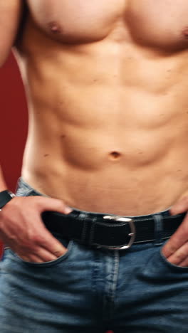 naked torso of athlete. muscular body of a sportive athlete in jeans. healthy sportsman in the studio. close-up. vertical video