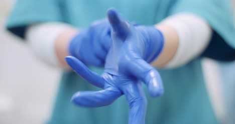 female surgeon putting on protective gloves 1