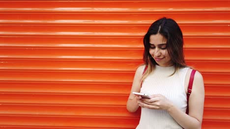 cámara lenta: hermosa joven usa teléfono inteligente y texto con fondo naranja y rojo