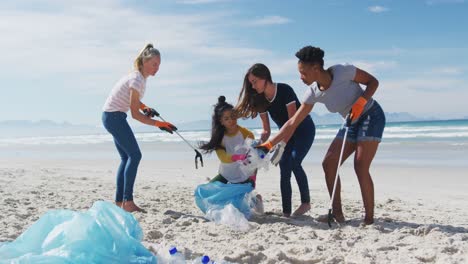 Diverse-group-of-female-friends-putting-rubbish-in-refuse-sacks-at-the-beach