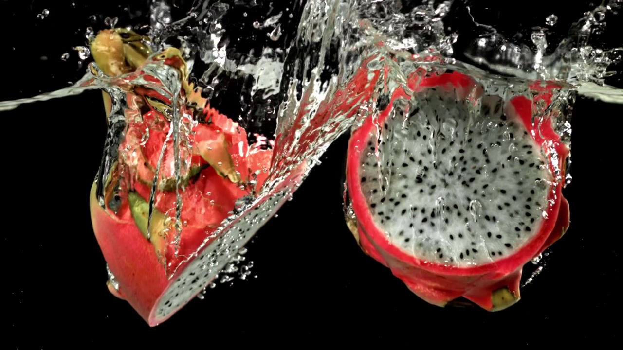 Metà di dragon fruit vivaci che schizzano nell'acqua al rallentatore
