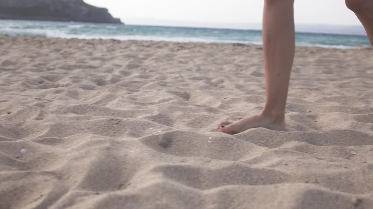 mujer caminando por la arena blanca de una playa mediterránea