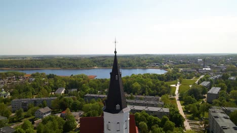 Drone-shot-of-the-city-church-Siauliai,-Cathedral-of-Saints-Peter-and-Paul,-tower-on-a-sunny-day-by-the-river-Siauliai,-Lithuania