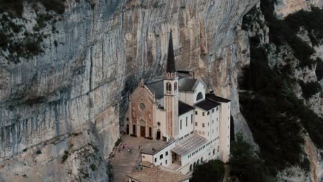 Point-of-interest-drone-shot-with-a-mountainside-beautiful-white-church,-sanctuary-between-tall-mountains,-cinematic-color-grade