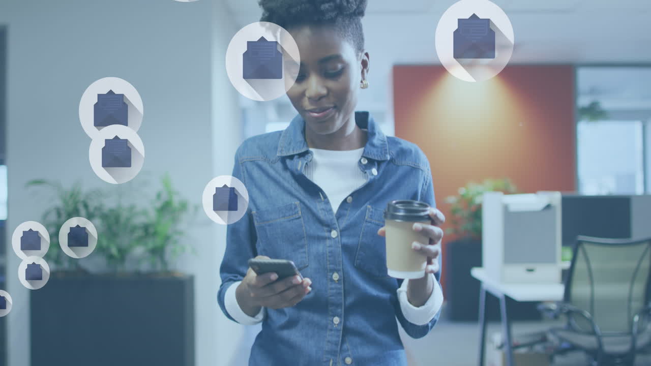 Animation of email icons over african american businesswoman using smartphone in office