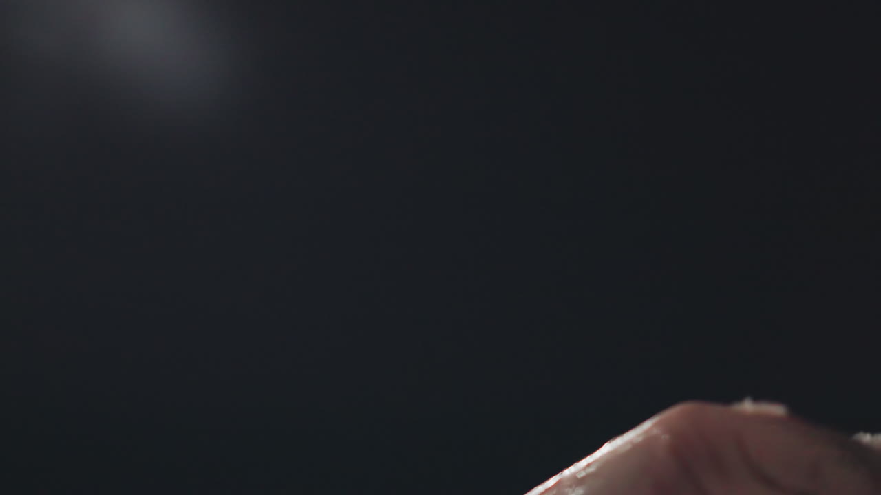Close up of female hand spinning gently in night air with melted snow glistening on fingertips, capturing soft reflections and delicate movement against dark background under subtle illumination