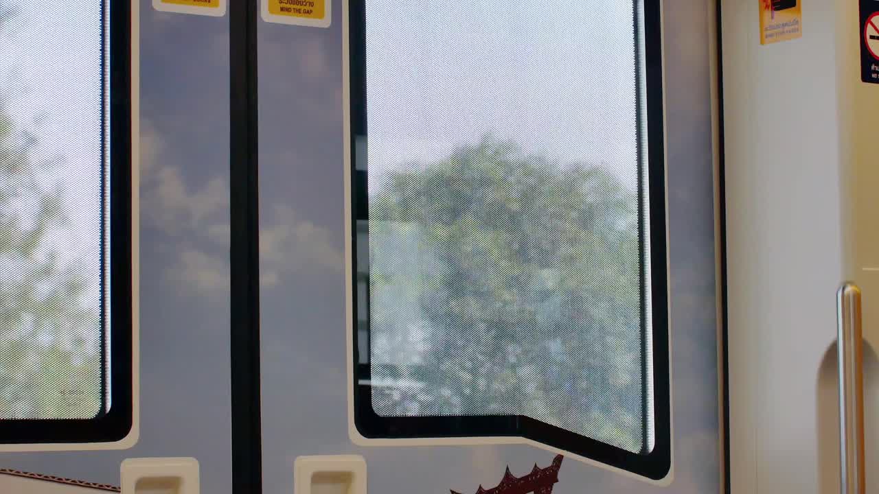 View from inside skytrain -public transportation in Bangkok. Outside view from the window on the train's door