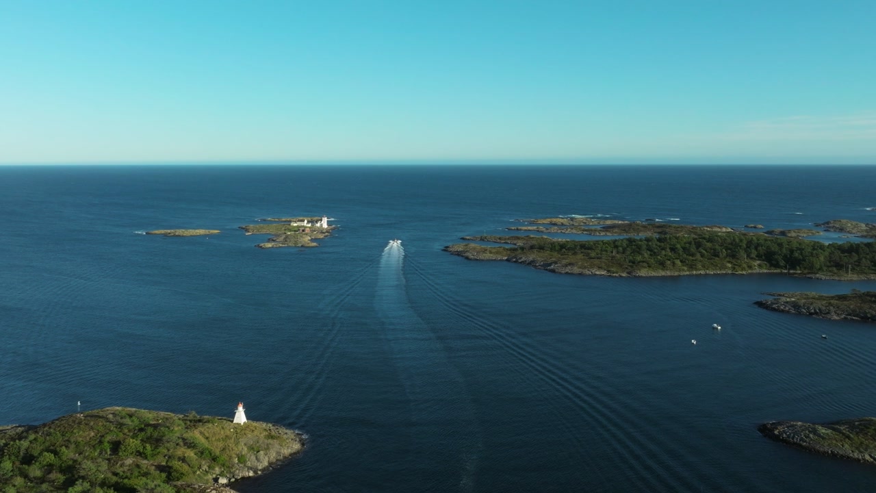 A boat moves gracefully through shimmering blue waters surrounded by serene islands and lush greenery under a clear sky. The scene captures the beauty of nature and tranquility.