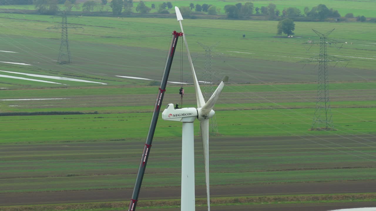 Uomo in piedi su una turbina eolica durante la manutenzione, riprese da drone.