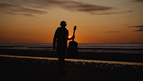 man running with guitar in back sand beach at sunset-16