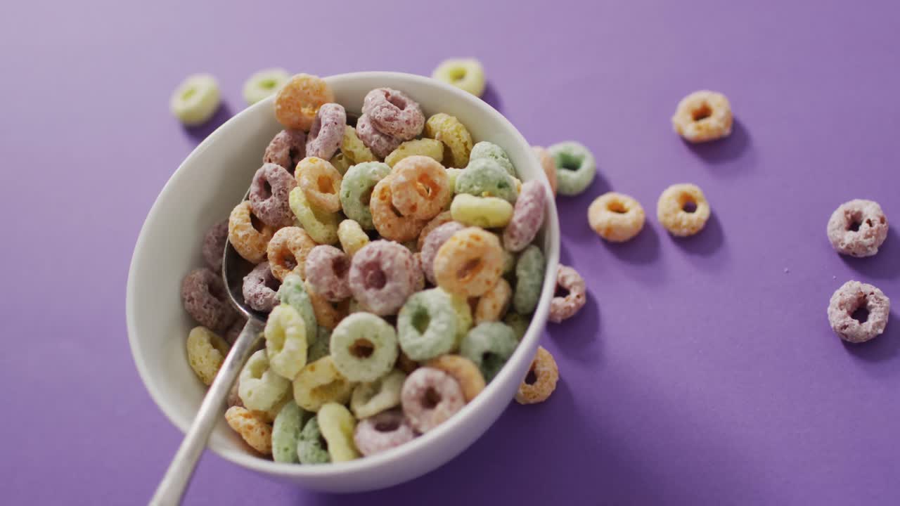 video de coloridos cereales de desayuno con tazón y cuchara sobre fondo púrpura