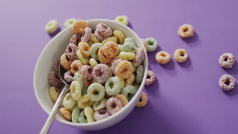 video of colorful breakfast cereals with bowl and spoon on purple background