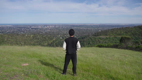 Vista-Trasera-De-Un-Hombre-Sikh-Punjabi-Indio-Mirando-La-Hermosa-Vista-De-La-Montaña-Verde,-El-Bosque-Y-La-Ciudad