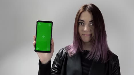 retrato de una mujer con un teléfono inteligente de pantalla verde en la mano que está llamando para verlo