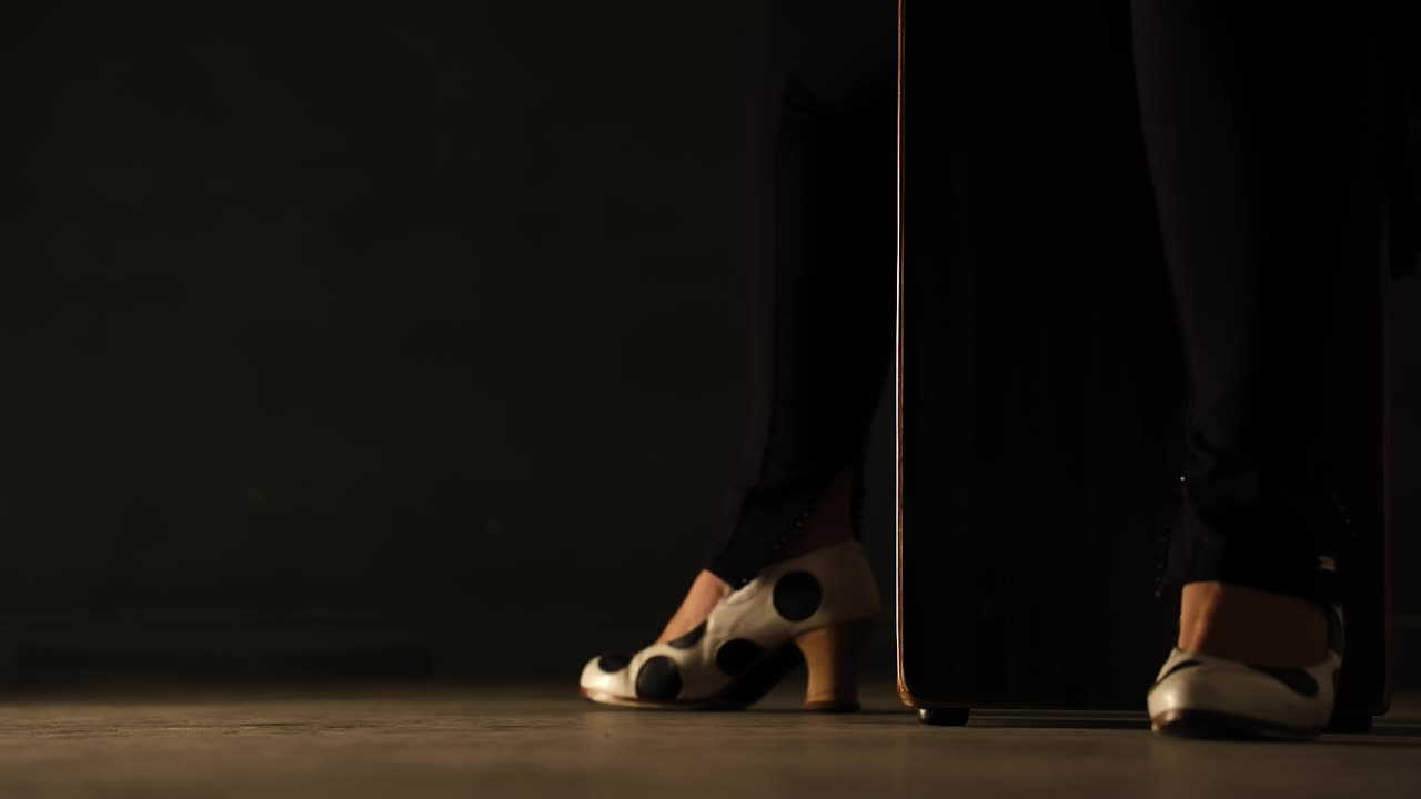 Flamenco dancer approaching cajon and beating her hand on its side. Static