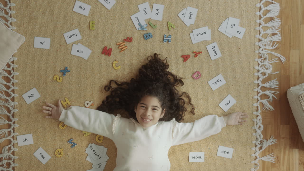 Menina Feliz Deitada Entre Fichas de Palavras e Letras do Alfabeto