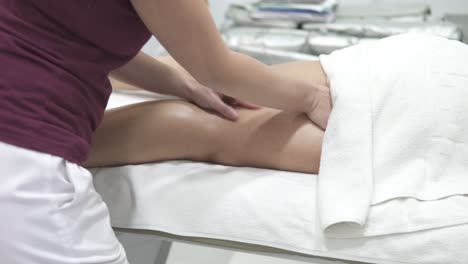 Hand-held-shot-of-a-masseuse-massaging-a-patient's-thigh-on-a-table